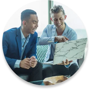 Two men discussing and viewing laptop together.